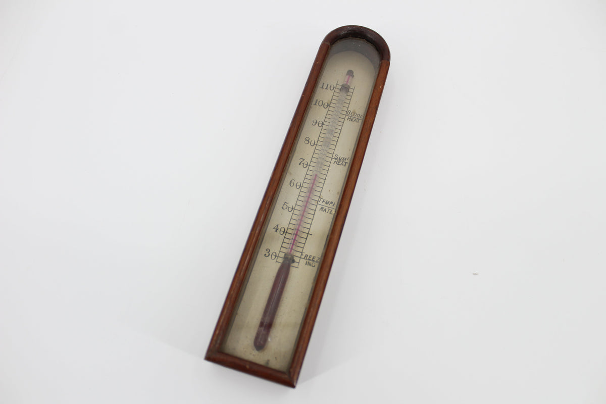 An 18th-century thermometer in a wooden case on a white background